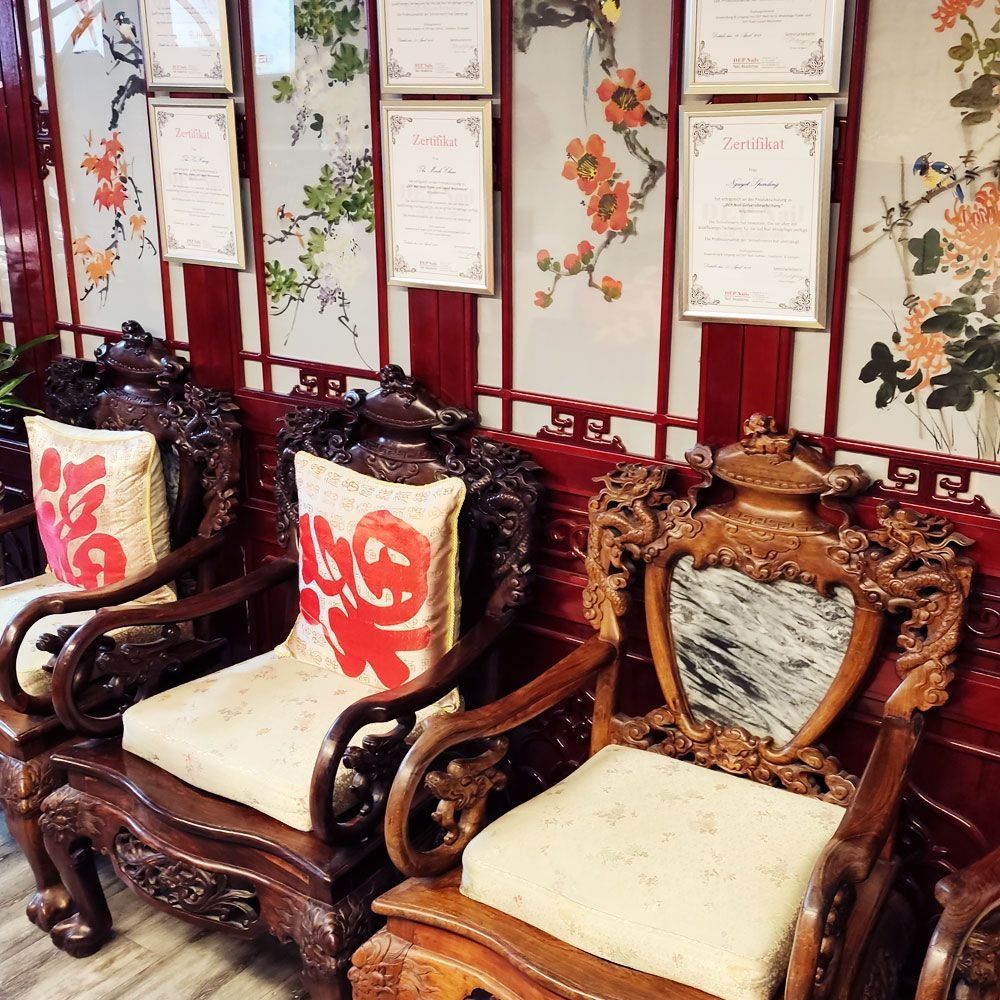 Dunkelbraune Stühle im asiatischen Stil vor einer Wand mit Zertifikaten